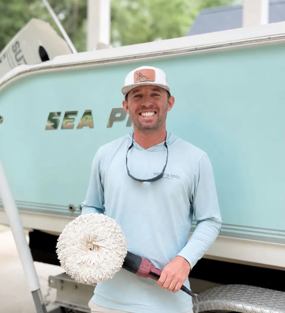Brice Sanders holding a rotary polisher with a wool pad beside a Sea Pro hull